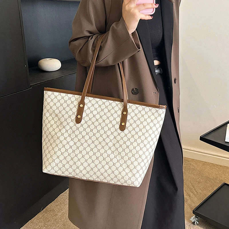 A model wearing a sleek minimalist pu leather tote bag carried over the shoulder in a city setting
