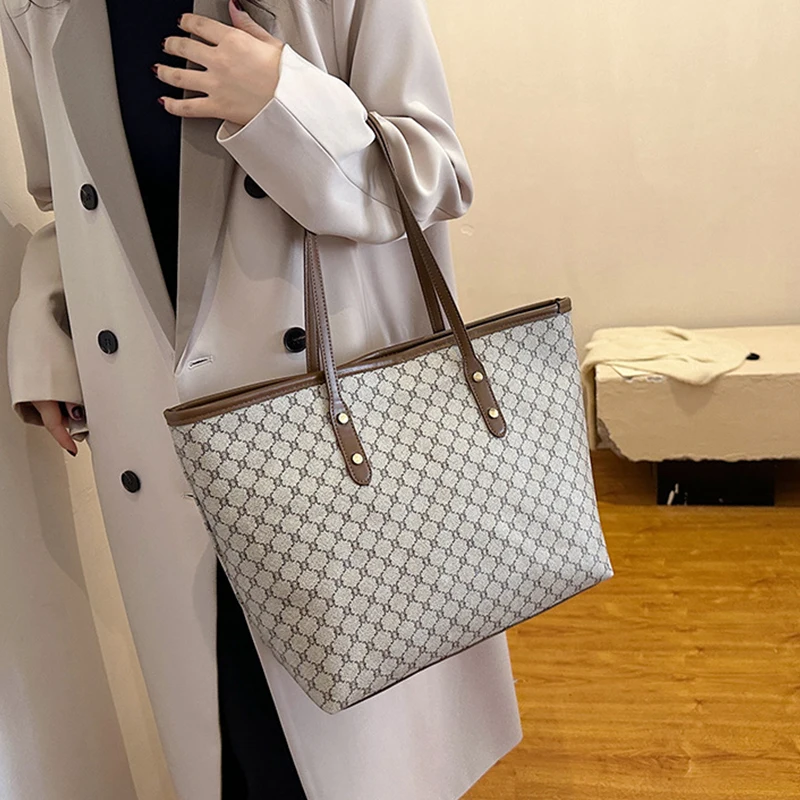 A model wearing a sleek minimalist pu leather tote bag carried over the shoulder in a city setting