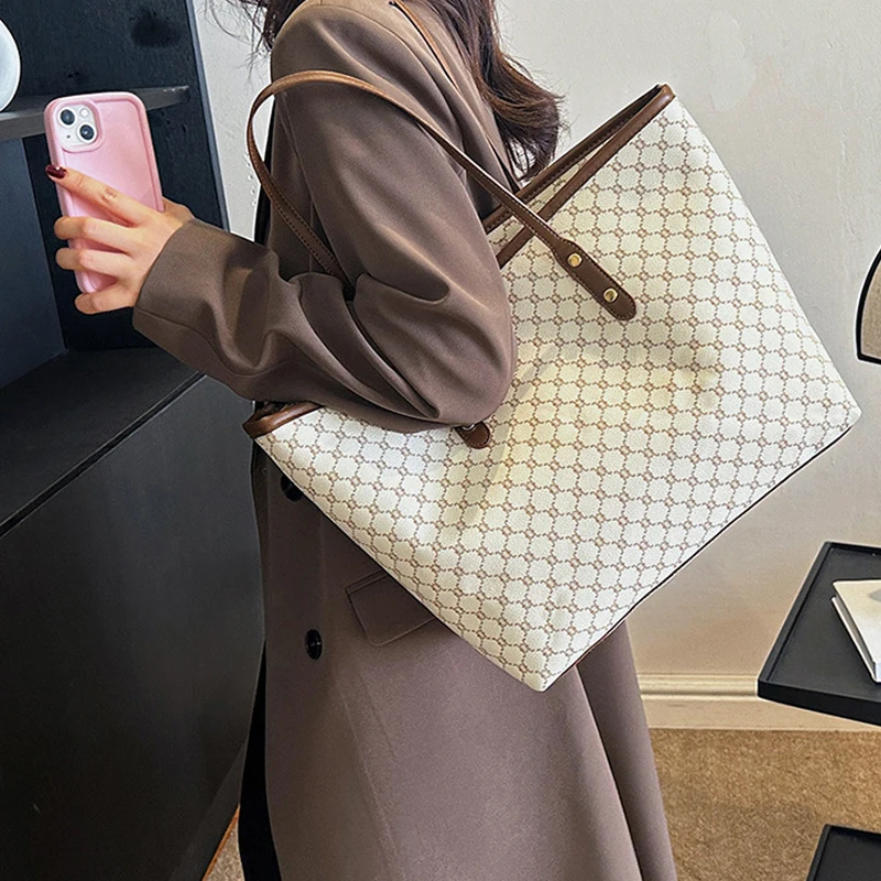 A model wearing a sleek minimalist pu leather tote bag carried over the shoulder in a city setting