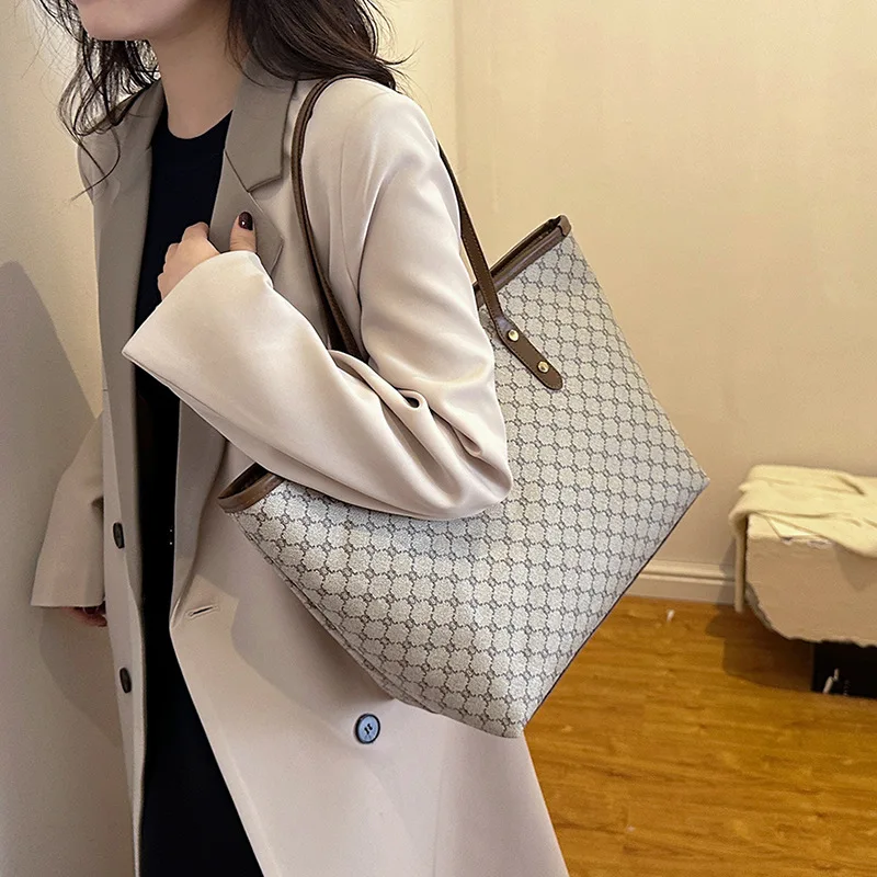 A model wearing a sleek minimalist pu leather tote bag carried over the shoulder in a city setting