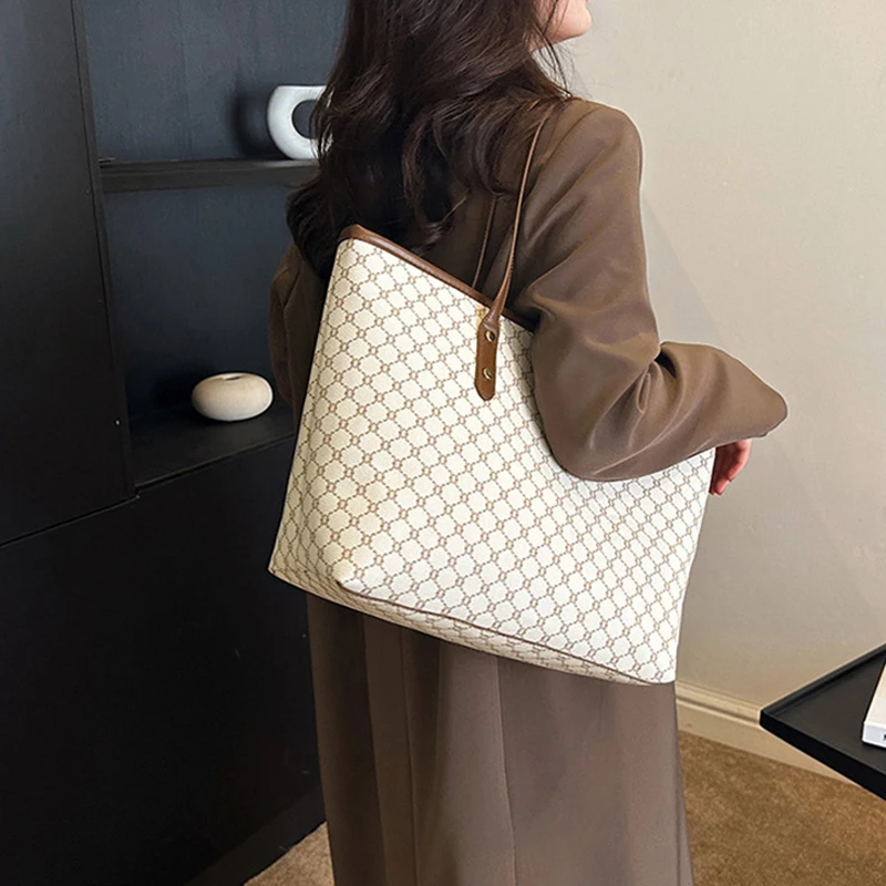 A model wearing a sleek minimalist pu leather tote bag carried over the shoulder in a city setting